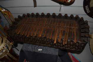 An African carved hardwood plucked idiophone musical instrument profusely carved with repeating