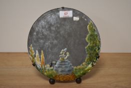 An early 20th Century circular bevelled edge mirror with hand painted design and raised on an