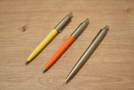Two Parker Jotter ballpoint pens in retro yellow and retro orange and a silver propelling pencil.