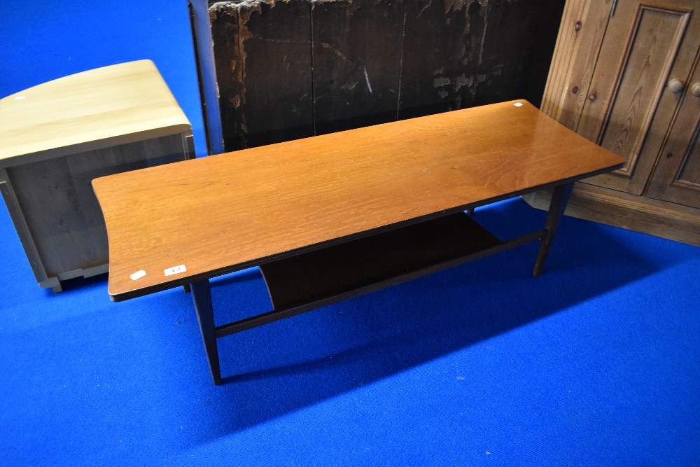 A vintage teak coffee table of stylised design, possibly over varnished