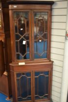 An Edwardian mahogany full height corner display having astral glazing to top and bottom sections