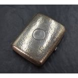 An Edwardian silver rectangular cigarette case having planished decoration and a circular