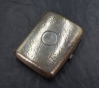 An Edwardian silver rectangular cigarette case having planished decoration and a circular