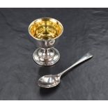 An Elizabeth II cased silver egg cup and spoon set, having a slightly flared rim and beaded