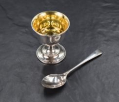 An Elizabeth II cased silver egg cup and spoon set, having a slightly flared rim and beaded