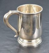 A George V silver tankard, of plain cylindrical form with, scrolled handle, reeded rim and stepped