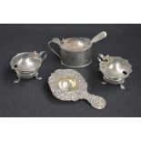 A group of silver table wares, comprising a decorative embossed tea strainer having cherubs and