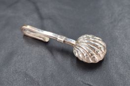 A silver skirt lifter having a scallop shell design, marked 925, 7.9g, some wear to clip.