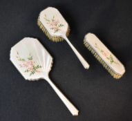 An Elizabeth II three-piece silver dressing table set having white guilloch enamel and floral