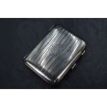A George V silver cigarette case, having vertical engine turned decoration with a circular cartouche
