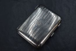 A George V silver cigarette case, having vertical engine turned decoration with a circular cartouche