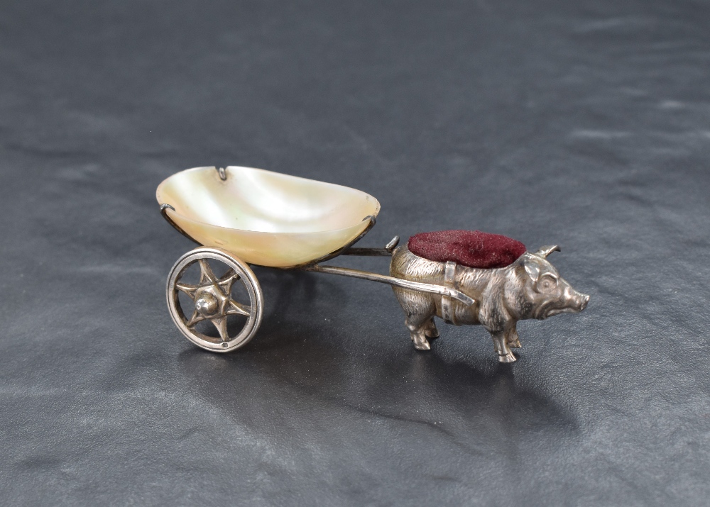An Edwardian silver novelty pin cushion modelled as a pig pulling a cart fashioned from mother-of-