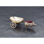 An Edwardian silver novelty pin cushion modelled as a pig pulling a cart fashioned from mother-of-