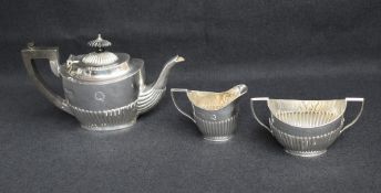 A group of three silver tea wares, comprising a tea pot having wooden handles, sugar and milk each