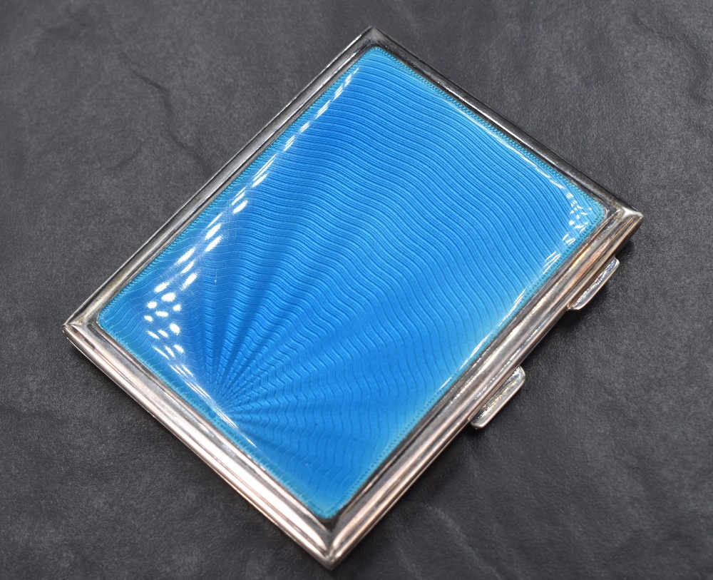 A George V silver cigarette case of rectangular engine turned form having blue guilloche enamel to