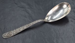 A 20th century American white metal serving spoon, having an oval bowl and profusely cast handle