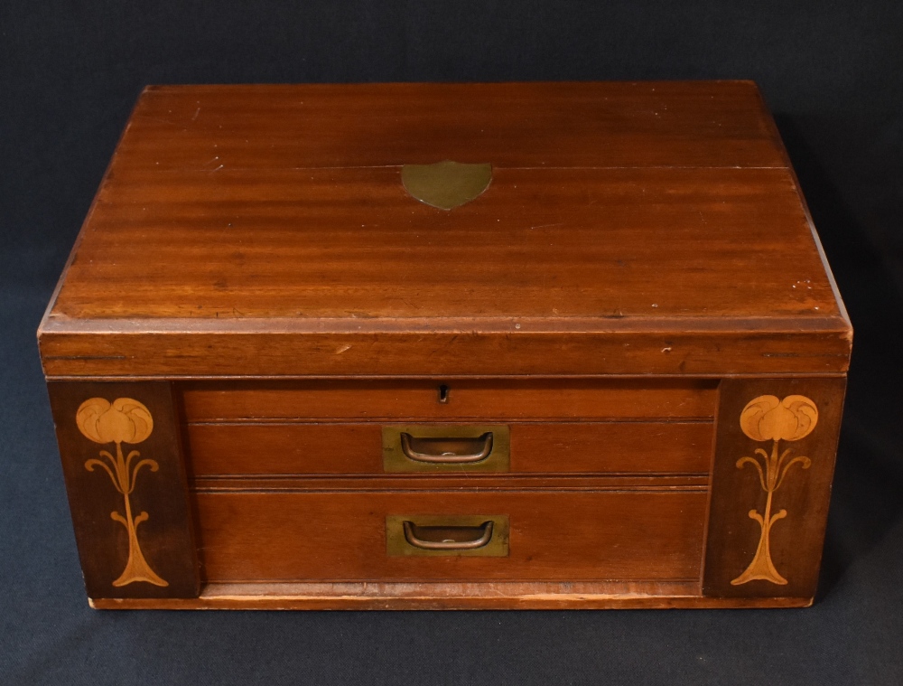 An Art Nouveau mahogany canteen, having a central brass shield inlay, brass handles and decorative