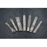 A group of seven silver needle cases, including one of elongated oval form having embossed bead