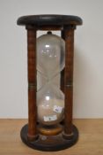 An antique maritime hourglass,having four turned spindles, capped with metal bands to centres and