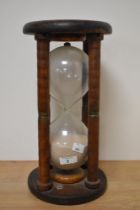 An antique maritime hourglass,having four turned spindles, capped with metal bands to centres and