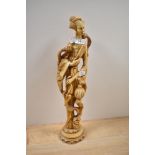 A large cast resin or ivory style figural study of a robed female with exotic birds, measuring