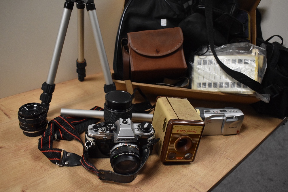 An assorted collection of cameras and equipment including a vintage Olympus camera, tripods, and