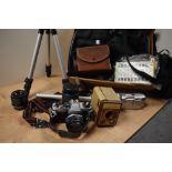 An assorted collection of cameras and equipment including a vintage Olympus camera, tripods, and