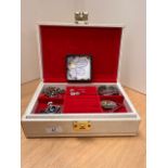 A cream jewellery box with red velvet lining, containing an assortment of costume jewellery