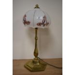 An early 20th century brass lamp, having opaque glass shade with flower and swag design.