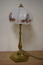 An early 20th century brass lamp, having opaque glass shade with flower and swag design.