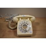 An early to mid-20th Century bakelite rotary dial telephone in cream, measuring 12cm high