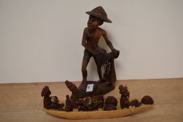 A carved Indian study of a gent in primitive attire and a carved wooden boat with African figures.