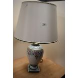 A 20th Century Italian porcelain table lamp, having a cream coloured shade, and floral decorated