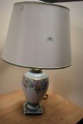 A 20th Century Italian porcelain table lamp, having a cream coloured shade, and floral decorated