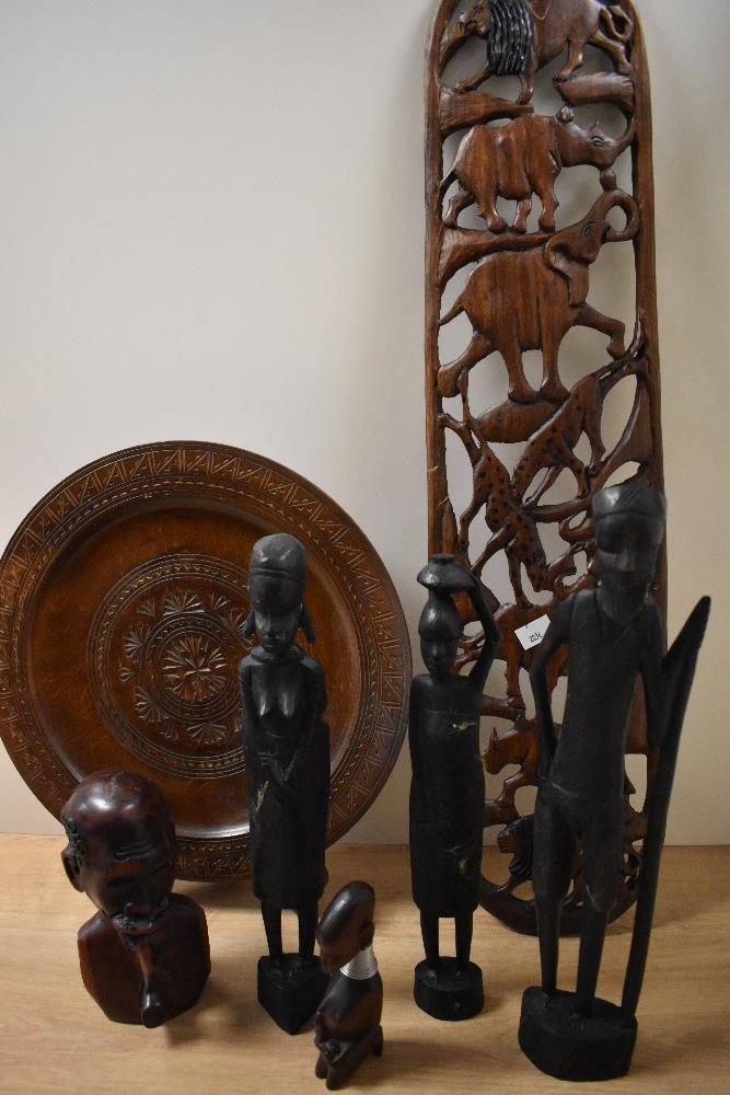 An African hardwood carved wall plaque, of bowed form, decorated with animals including a lion,