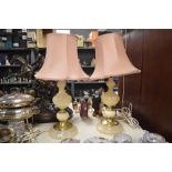 Two traditional brass and onyx or onyx effect table lamps, with peach shades.