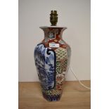 A vintage Chinese lamp base, having mountain and tree scene, surrounded by multi coloured motifs.