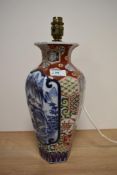 A vintage Chinese lamp base, having mountain and tree scene, surrounded by multi coloured motifs.
