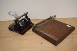 A vintage hole punch and a wooden paper guillotine.