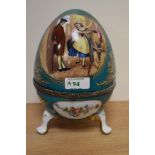 A Continental porcelain footed egg trinket box, decorated with vignettes of floral arrangements