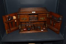 An early 20th century gents smokers cabinet with integrated pip racks, drawers and a selection of