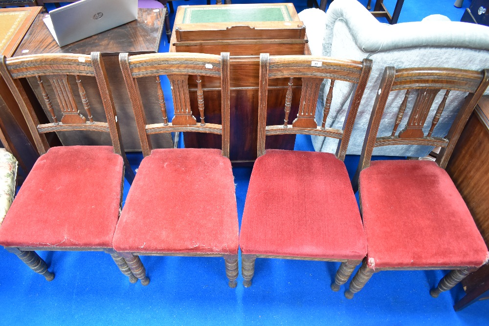 A set of four Victorian oak dining chairs having rail and spindle back, over stuffed seats on turned