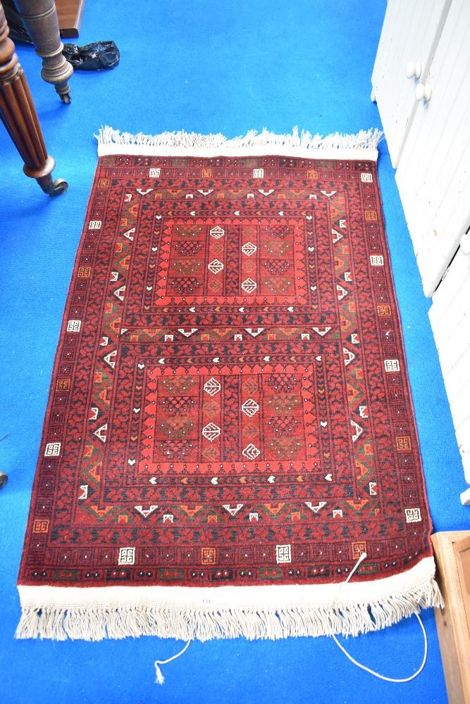 A traditional Persian rug, for prayer or fireside use having red ground with cream, green and orange