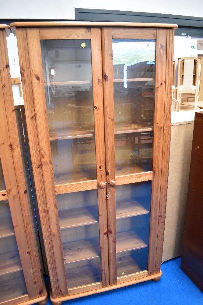 A modern pine glass fronted slim bookcase