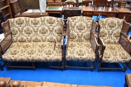A late 19th or early 20th Century three piece lounge suite having oak twist frae, bergere cane sides
