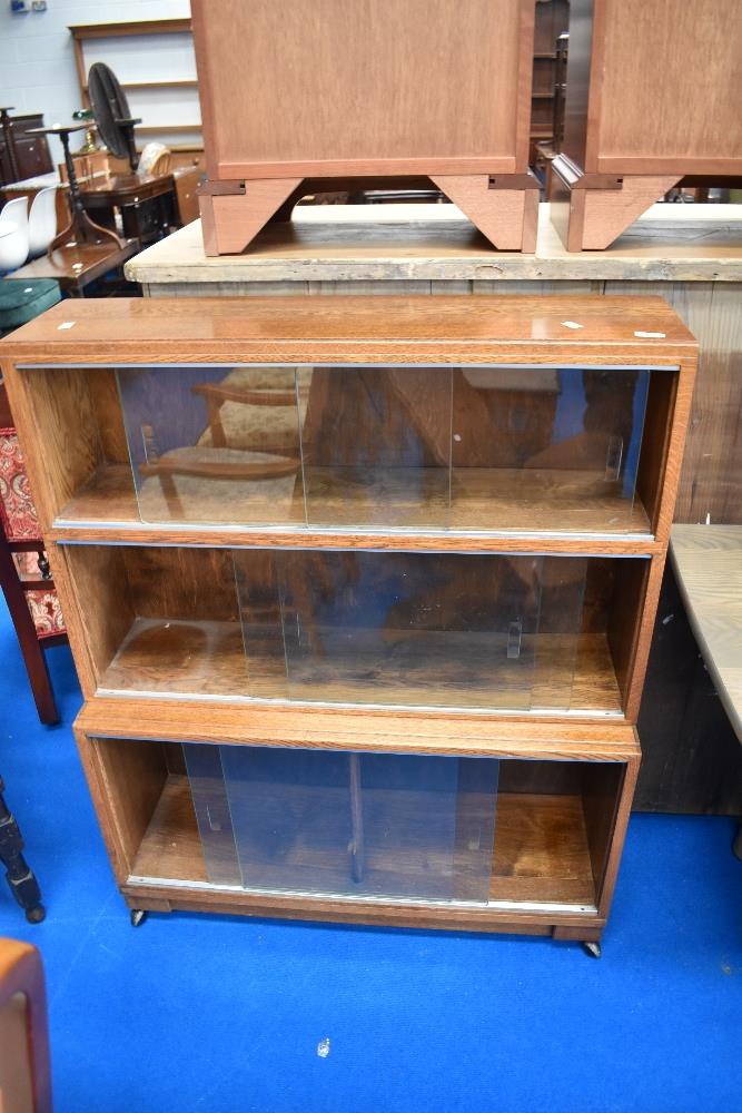 A minty or similar stacking bookcase, in oak having three tiers and castors