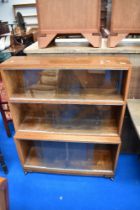 A minty or similar stacking bookcase, in oak having three tiers and castors