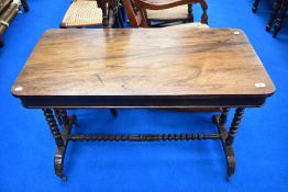 A Victorian mahogany and walnut sofa style side table having turned supports and stretcher
