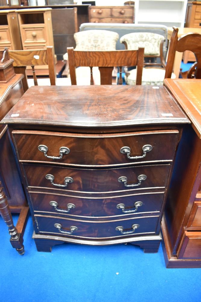 A reproduction serpentine fronted chest of four drawers