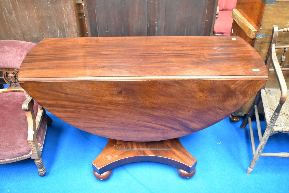 A William IV mahogany drop leaf dining table on typical platform base with bun feet